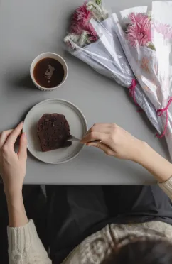 花束をテーブルにおき、デザートを食べ始める女性。